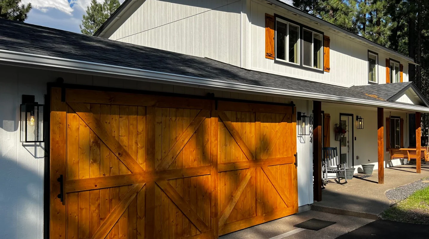 Custom wood barn-style garage door on a white two-story home