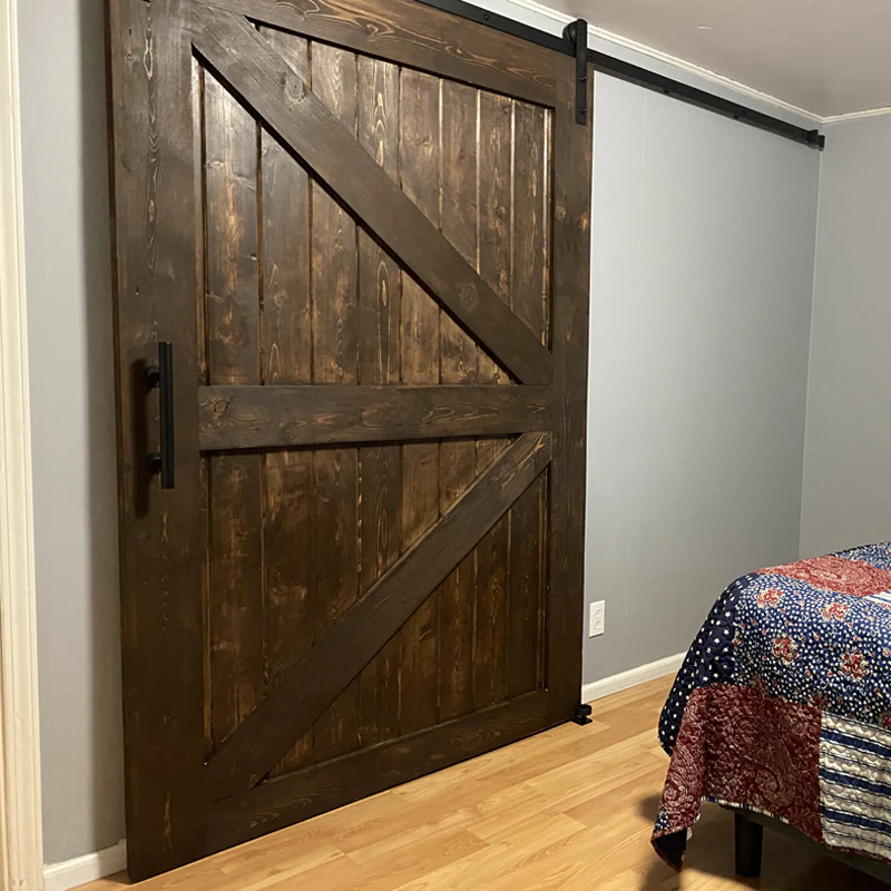 Dark stained wood sliding barn door on black hardware in a bedroom